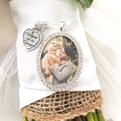 Spanish Bridal Memorial Photo Bouquet Charm in oval shape with clear rhinestones around edge of pendant. Image size is roughly 30mmx40mm. Comes with heart shape charm that reads, Siempre en mi Corazon. Pendant and charm come on a white ribbon to attach to bridal bouquet.
