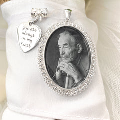 Bridal Memorial Photo Bouquet Charm in oval shape with clear rhinestones around edge of pendant. Image size is roughly 30mmx40mm. Comes with heart shape charm that reads, You are always in my heart. Pendant and charm come on a white ribbon to attach to bridal bouquet.