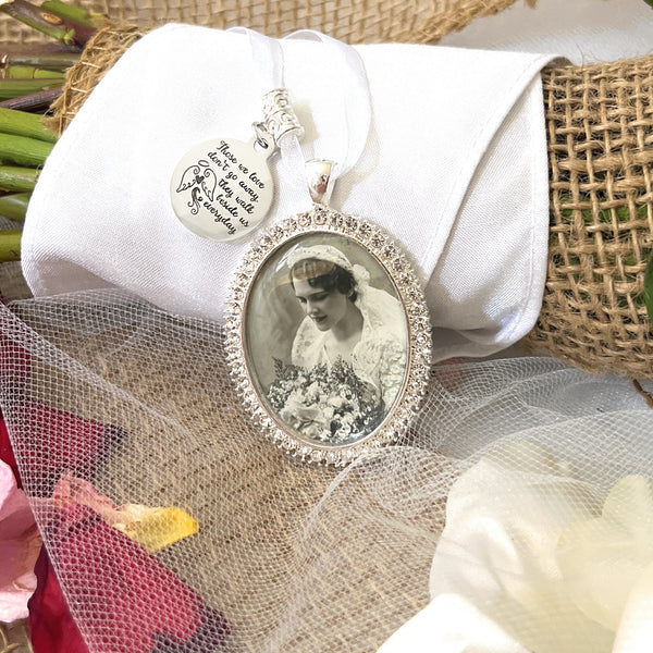 memorial bouquet charm with photo. Oval shape with rhinestones around the edges. Image size is roughly 30x40mm in size. Comes with a saying charm reads: Those we love don't go away they walk beside us everyday. Also comes with a ribbon to attach to the brides bouquet.